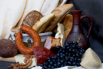 Still-life. Wine. Glass of wine. Cheese. Sausage. Bread. Basket. Grape. A decanter of wine. Nuts...