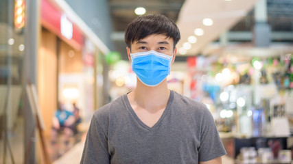 Fototapeta na wymiar Asian man is wearing surgical mask in shopping mall