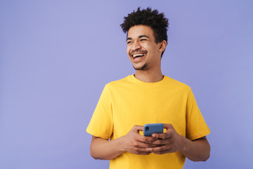 Photo of funny african american man laughing and using smartphone