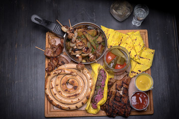 Patella, domestic sausage, meat, shashlik, kebab, salt pancakes, pickled orugs and tomatoes and sauces. food set. For the menu of cafe. wooden table. side view. macro photo