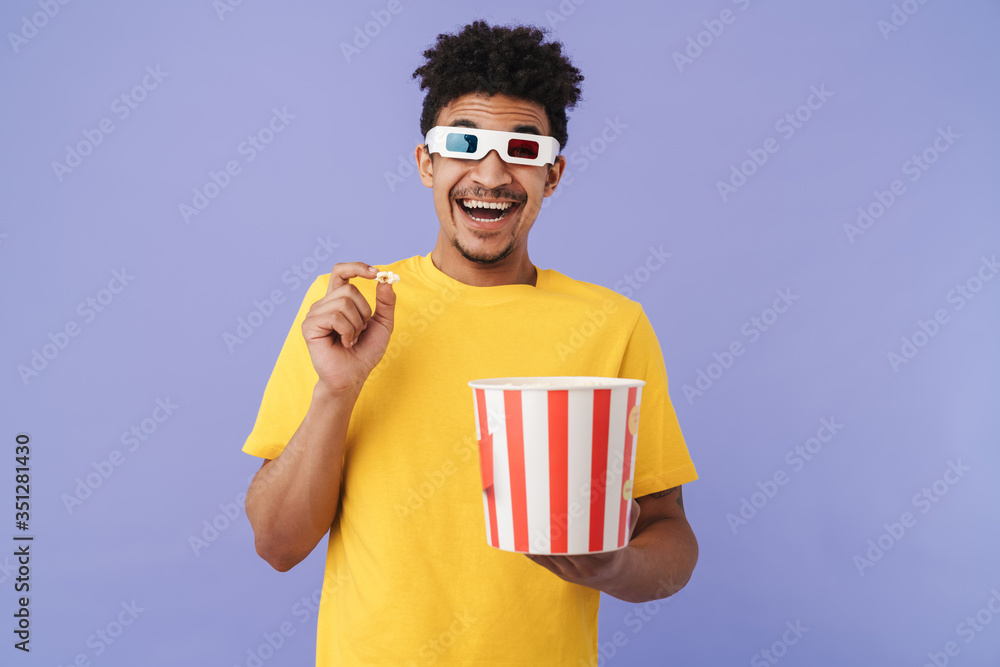 Wall mural Photo of african american man watching movie and eating popcorn