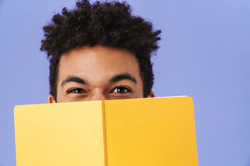 Photo of african american man covering his face with exercise book