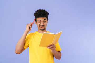 Photo of african american man grimacing and making notes in planner