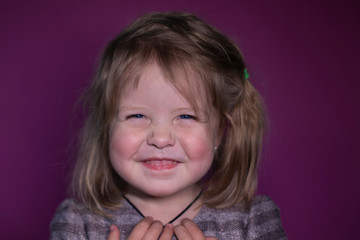 portrait of happy a three year old blond girl with blue eyes on a pink background