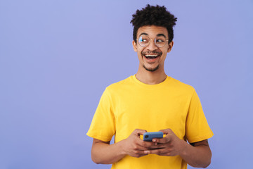 Photo of excited african american man smiling and using smartphone