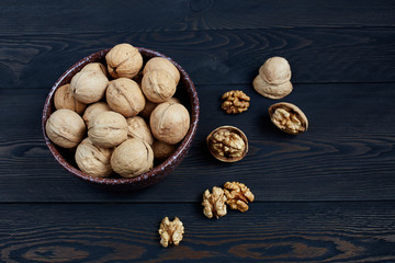 Walnut kernels in a bowl on a dark wooden background.