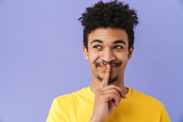 Photo of african american man smiling and showing silence gesture
