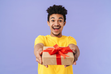 Photo of happy african american man holding out gift box and smiling