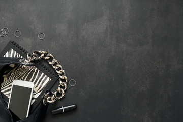 Black leather bag with chain, white phone, zebra print, silver thin rings on a black background