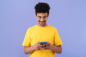 Photo of joyful african american man smiling and using smartphone
