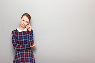 Portrait of serious focused girl touching temple with finger