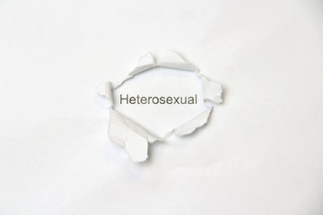 Word heterosexual on white isolated background, the inscription through wound hole in paper. Concept of gender identity and sexual minorities. Stock photo for web and print with empty space for text
