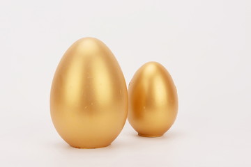 Two golden eggs isolated in a white background.