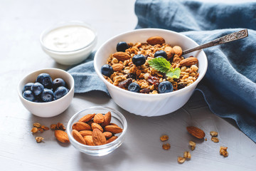 Baked granola with yogurt and blueberries on a gray table.