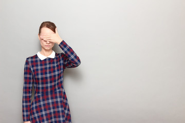 Girl is covering her eyes with hand, not wanting to look at something