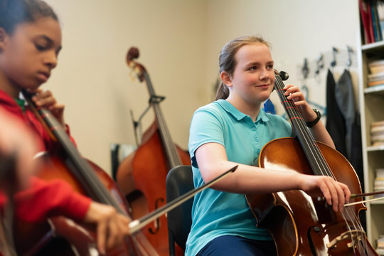 Teenage girls playing cellos in classroom