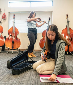 Teenage girls rehearsing violins in classroom