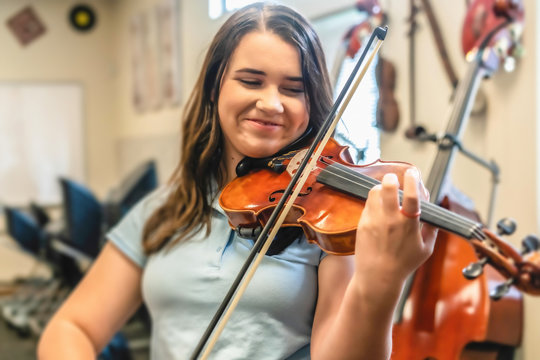 Smiling teenage girl playing violin in classroom