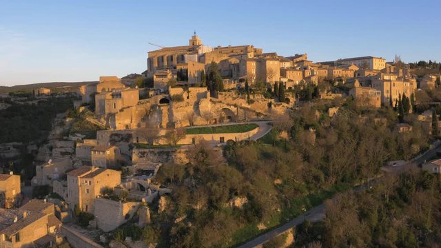 Houses built on steep rock faces in French town of Gordes. Aerial view at sunrise