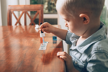 Little boy laboratory activity with colored water, pipette and pieces of glass. Homeschooling...