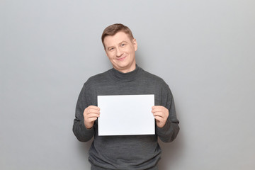 Portrait of happy man holding white blank paper sheet in hands