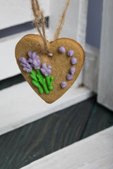 Gingerbread decorated with glaze. Made in the shape of a heart. Hanging on a rope. Against the background of white boards.