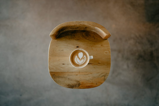 taza de café con dibujo late art sobre una silla de madera