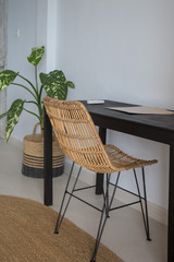 Wooden work desk and modern rattan chairs in beachy boho chic bedroom. Eco friendly furniture in neutral tones.