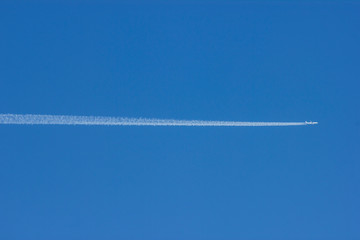 A passenger jet plane flying accross a deep blue sky leaving a long white jet stream trailing...