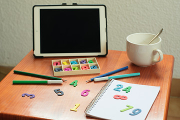 Mesa de estudio con tablet, libreta y colores. 