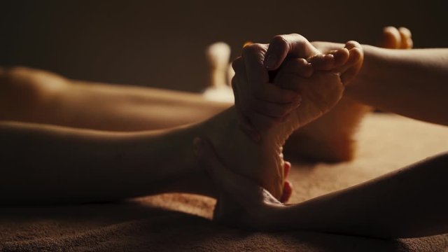 Professional foot massage. Authentic footage of luxury spa treatment. Charming light. Shallow depth of field. Stylized and colored.