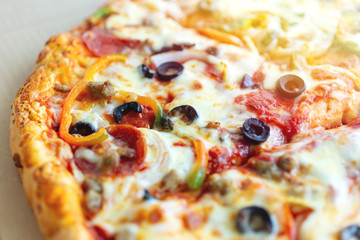 Close up texture of large cheesy pizza with olives, bell paper and salami, background macro