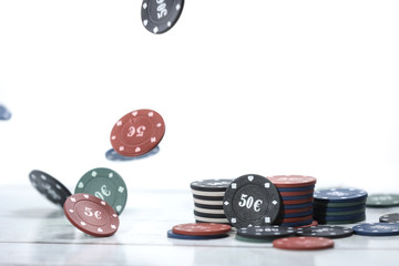 Falling poker playing chips on a wooden table and white background. Online gambling. Addiction. Falling poker chips. 