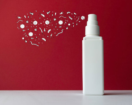 A spray mist with illustrated microbiomes relating to skin health coming out from the bottle.  White bottle against a white background with space for copy text.