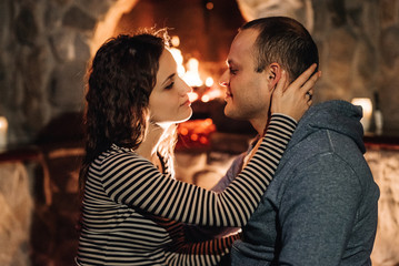 guy and girl are sitting on the background of a burning fireplace