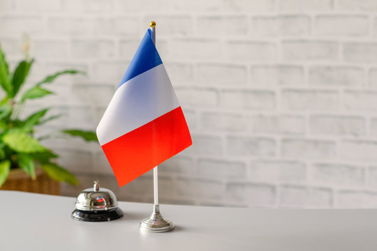 Silver vintage bell with national flag of France on reception desk with copy space. Hotel service. Travel, tourism. Selective focus. Europe, Concept.