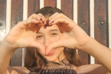 teenager smiling and making a heart with her hands