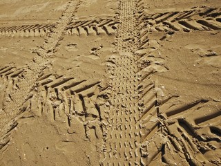 foto che rappresenta la geometricità lasciate dalle tracce di pneumatici vari di automezzi sulla sabbia bagnata