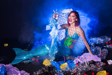 Obraz na płótnie Canvas Ocean plastic pollution concept. Mermaid lives to polluted habitat.