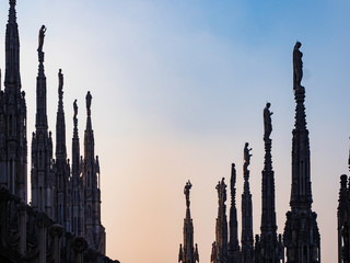 Estatuas de piedra en las gárgolas del tejado de la catedral de Milan al atardecer