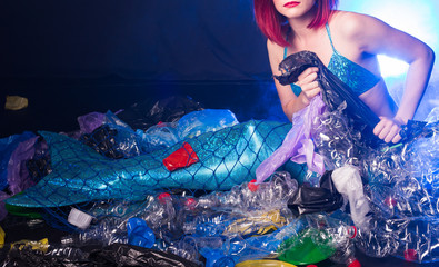 Ocean plastic pollution. Close-up of mermaid swimming in water with plastic garbage. Stop plastic pollution. Fairy tale and reality concept.