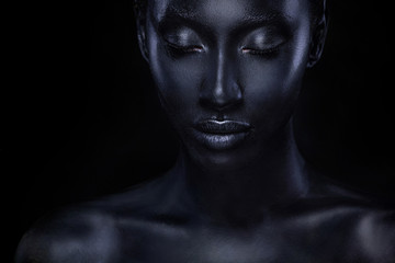 Frau mit schwarzer Körperbemalung. Fröhliches junges afrikanisches Mädchen mit Bodypaint. Ein erstaunliches Modell mit künstlerischem Make-up. Nahaufnahme Gesicht.
