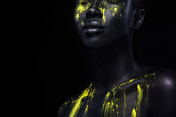 Frau mit schwarzer Körperbemalung. Fröhliches junges afrikanisches Mädchen mit Kunst-Bodypaint. Ein erstaunliches Modell mit gelbem Make-up. Nahaufnahme Gesicht.