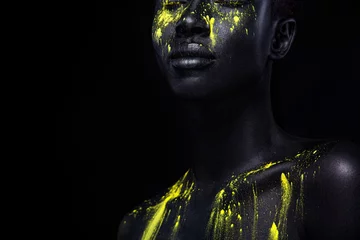 Frau mit schwarzer Körperbemalung. Fröhliches junges afrikanisches Mädchen mit Kunst-Bodypaint. Ein erstaunliches Modell mit gelbem Make-up. Nahaufnahme Gesicht. © Mike Orlov