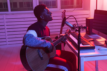 African american professional musician recording guitar in digital studio at home, music production...