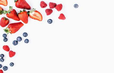 A lay out set of berries - strawberry, raspberry, blueberry isolated on grey background. Blank space for text in the middle
