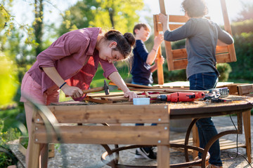 A teenage girl helps her family to build wooden planters for their permaculture vegetable garden