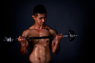 Fototapeta na wymiar The strong Asian man lifted his dumbbell regularly to keep his muscles strong and beautiful