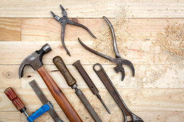 Top view of old and rusty toolset on natural pine wood workbench. Work and DIY concept.