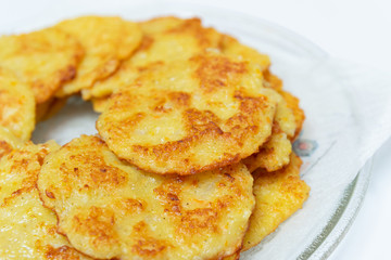 Homemade fried potato pancakes on a transparent plate.